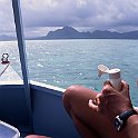 Sunbather on boat applying sun lotion, against an Indian Ocean island background